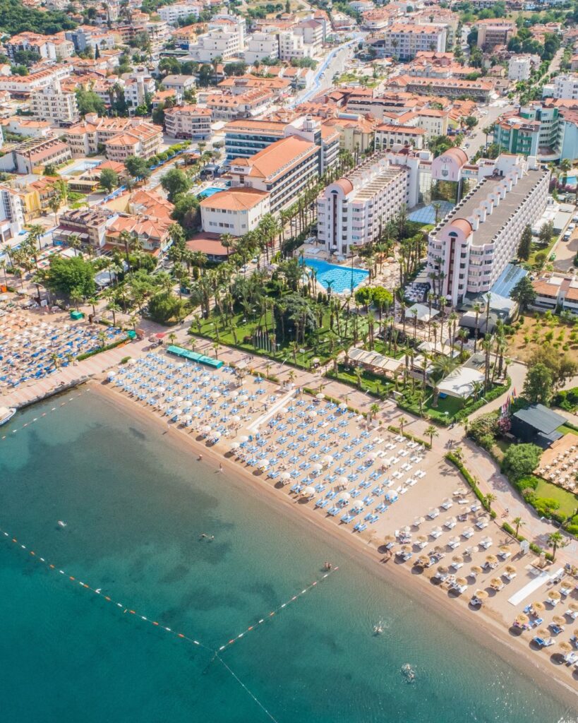 Letecký pohľad na hotel Aqua 5* v Dalamane pri pieskovo-kamienkovej pláži s ležadlami